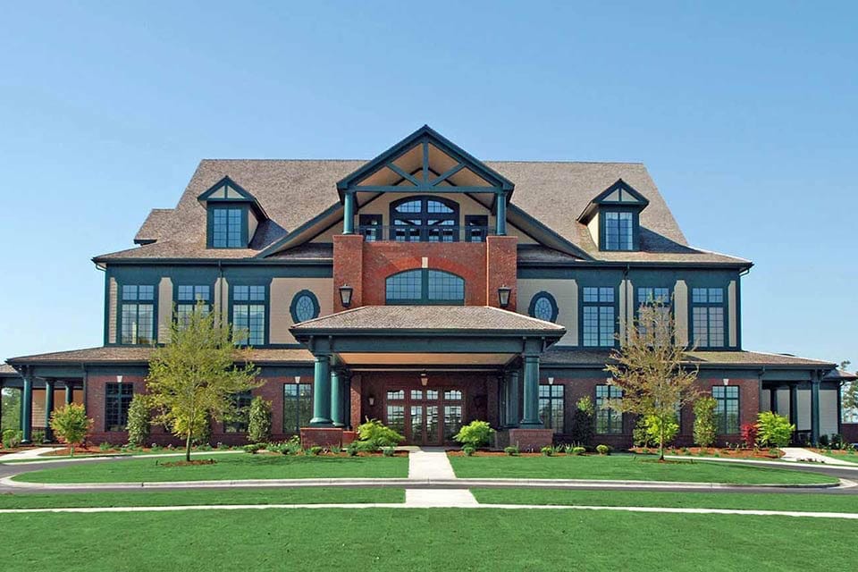 Elegant brick and siding clubhouse with grand entrance and landscaped lawn at River Landing community.