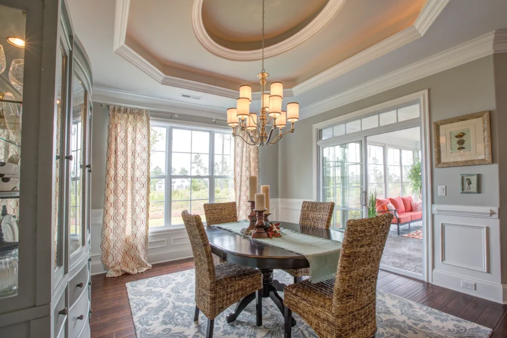 Bright dining room with round wooden table, wicker chairs, and warm natural light.