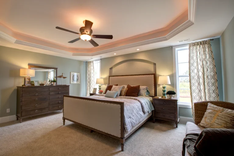 Modern beige master bedroom with tray ceiling, warm lighting, and elegant neutral decor.