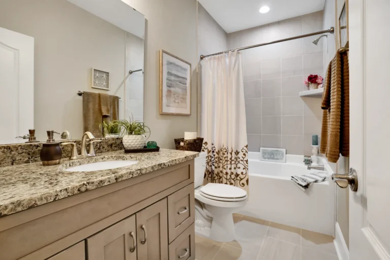 Modern beige bathroom with granite vanity, gold fixtures, and warm neutral decor accents.