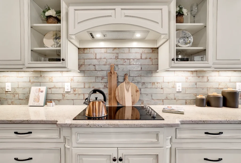 Modern rustic white kitchen with copper kettle, subway tile backsplash, and elegant cream cabinetry.