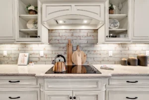 Modern rustic white kitchen with copper kettle, subway tile backsplash, and elegant cream cabinetry.