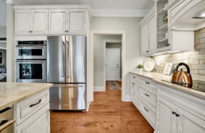 Bright white kitchen with quartz countertops, stainless steel appliances, and warm hardwood floors.
