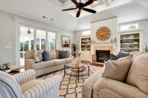 Elegant neutral living room with fireplace, coffered ceiling, and natural light through glass doors.