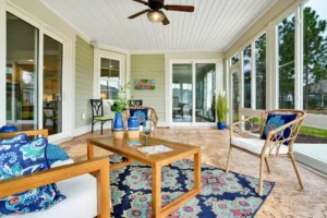 Bright sunroom with wood furniture, blue accents, and natural light overlooking lush greenery.
