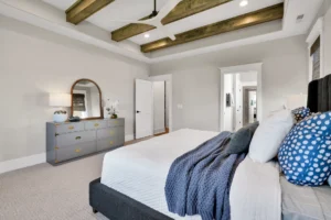 Modern bedroom with neutral decor, exposed wooden beams, blue accents, and elegant furnishings.
