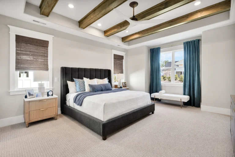Modern rustic bedroom with upholstered bed, blue accents, and exposed wooden ceiling beams.