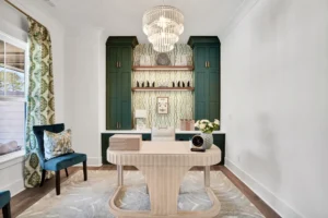 Elegant modern home office with green cabinetry, sculptural desk, and luxurious lighting.