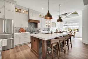 Modern white kitchen with large island, wood accents, and bronze pendant lighting.