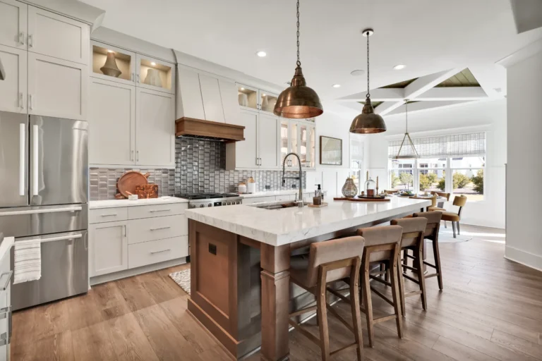 Modern white kitchen with large island, wood accents, and bronze pendant lighting.