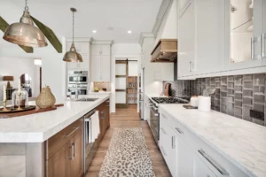 Modern galley kitchen with white quartz countertops, wood accents, and stainless steel appliances.