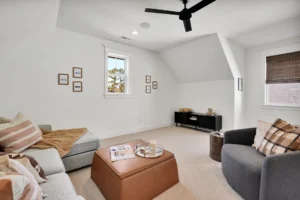Cozy modern living room with neutral decor, gray sectional, leather ottoman, and natural light.