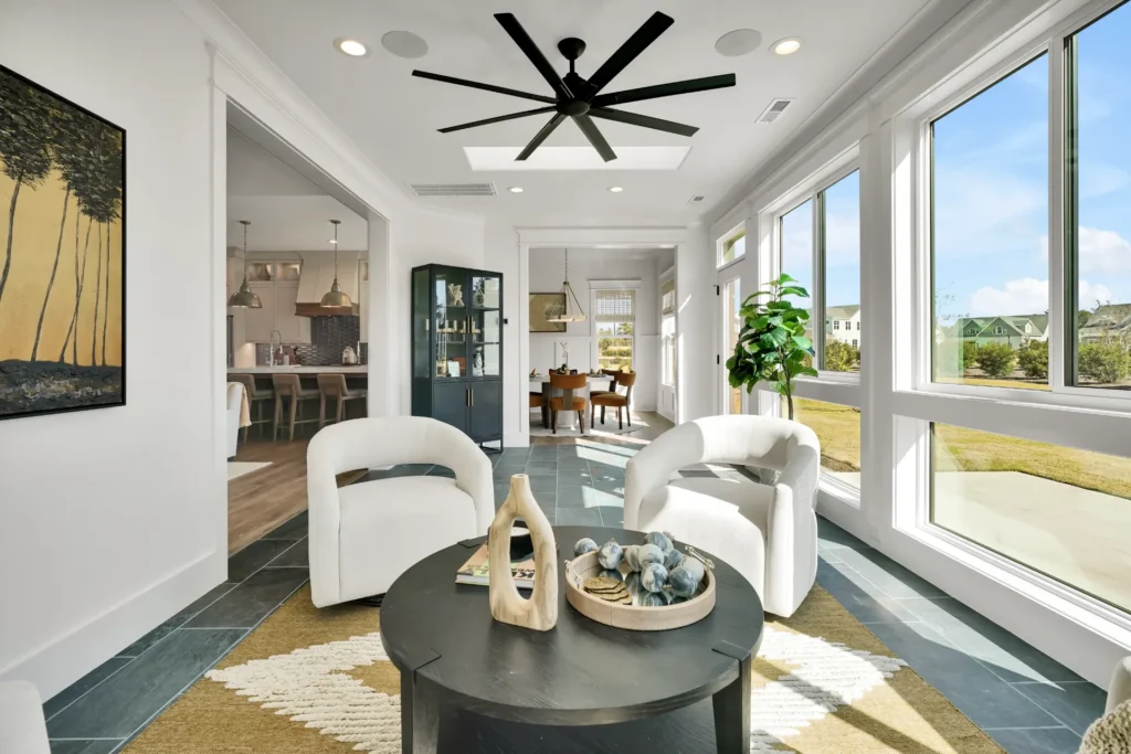 Bright modern minimalist living room with curved white chairs, black coffee table, and natural light.