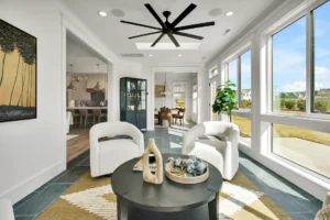 Bright modern minimalist living room with curved white chairs, black coffee table, and natural light.
