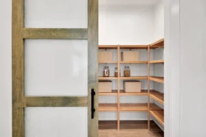 Rustic sliding door pantry with organized wooden shelves and modern farmhouse design.