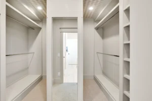 Modern white minimalist walk-in closet with open shelves, hanging space, and full-length mirror.