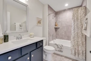 Elegant modern bathroom with navy vanity, white countertop, and taupe tile shower design.