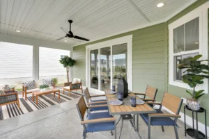 Modern covered patio with dining table, lounge seating, ceiling fan, and potted plants.