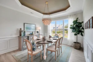 Elegant neutral dining room with round wooden table, crystal chandelier, and soft natural lighting.