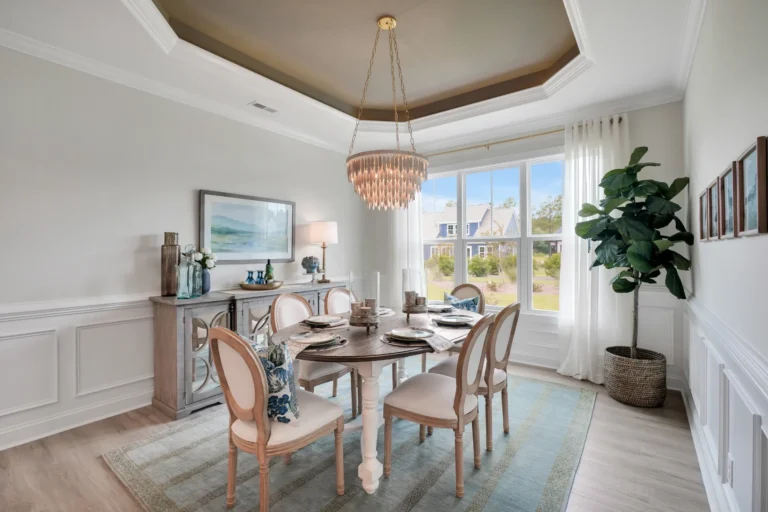 Elegant neutral dining room with round wooden table, crystal chandelier, and soft natural lighting.