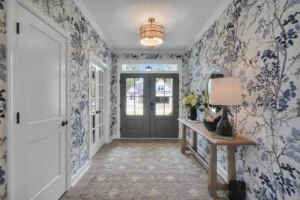 Elegant entryway with blue floral wallpaper, wooden console table, and dark gray double doors.