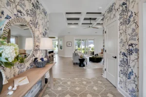 Bright entryway with blue floral wallpaper leading to a modern, light-filled coastal living space.