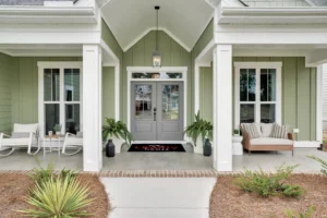 Sage green craftsman home with white trim, gray double doors, and a welcoming front porch.