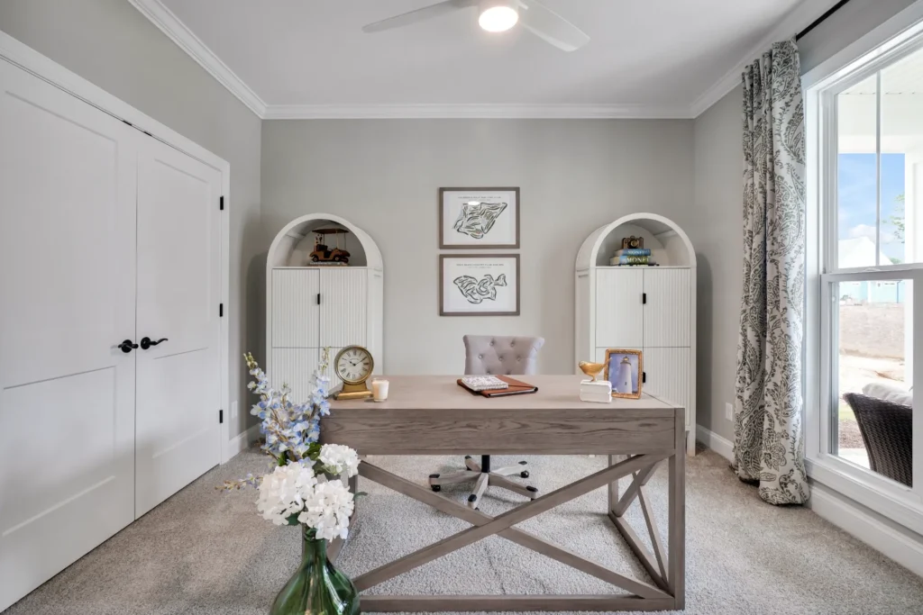 Bright modern home office with light wood desk, neutral decor, and natural sunlight.