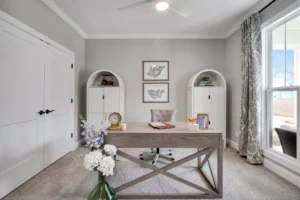 Bright modern home office with light wood desk, neutral decor, and natural sunlight.