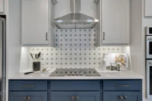 Modern kitchen with white quartz countertops, blue cabinets, and stainless steel range hood.