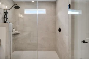 Modern walk-in shower with beige tiles, black fixtures, and glass enclosure featuring natural light.