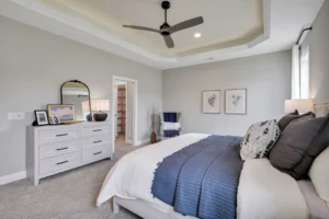 Modern gray bedroom with navy accents, white bedding, reading nook, and elegant contemporary decor.