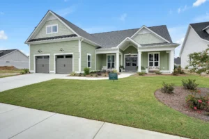 Modern sage green single-story home with white trim, two-car garage, and manicured front lawn.