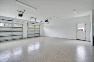 Bright modern two-car garage with polished epoxy floor, white walls, and automatic metal doors.