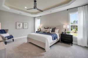 Modern bedroom with blue and neutral décor, wooden bed, natural light, and cozy seating.