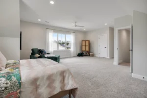 Modern neutral bedroom with soft gray walls, pink floral bedding, and cozy natural light.