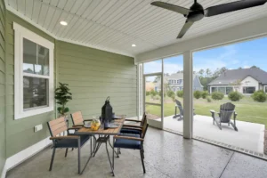 Screened patio with wooden dining table, ceiling fan, and backyard view for outdoor relaxation.
