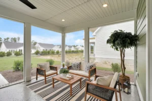 Modern screened porch with wooden furniture, striped rug, and airy outdoor seating area.