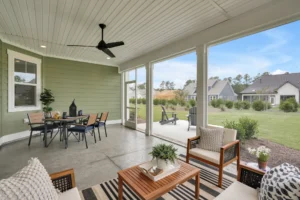 Modern screened porch with wood furniture, ceiling fan, and backyard view for relaxing outdoor living.