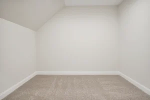 Bright small attic room with off-white walls, beige carpet, and a cozy minimalist feel.