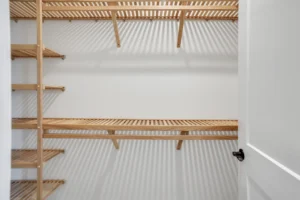 Minimalist walk-in closet with light wood shelves and white walls for bright, modern storage.