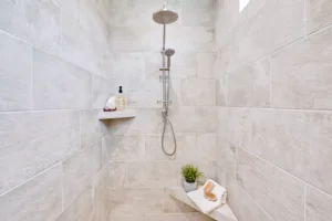 Modern gray tile walk-in shower with chrome rainfall head and minimalist spa-style decor.
