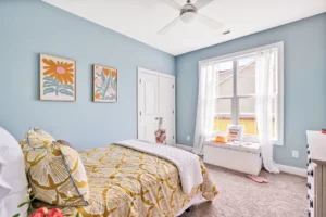 Cozy blue bedroom with golden accents, natural light, and a bright inviting atmosphere.