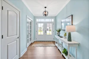 Bright light blue coastal farmhouse entryway with white accents and warm wood flooring.