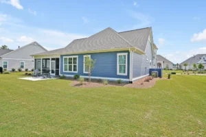Modern blue single-story suburban home with white trim, gray roof, and spacious green lawn.