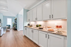 Bright open-concept kitchen with white cabinets, wood floors, and a light-filled brunch setup.