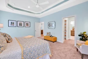Elegant blue primary bedroom with tray ceiling, gold bedding, and cozy decor.