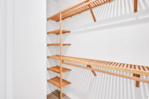 Modern walk-in closet with light wood shelves, white walls, and bright, minimalist design.