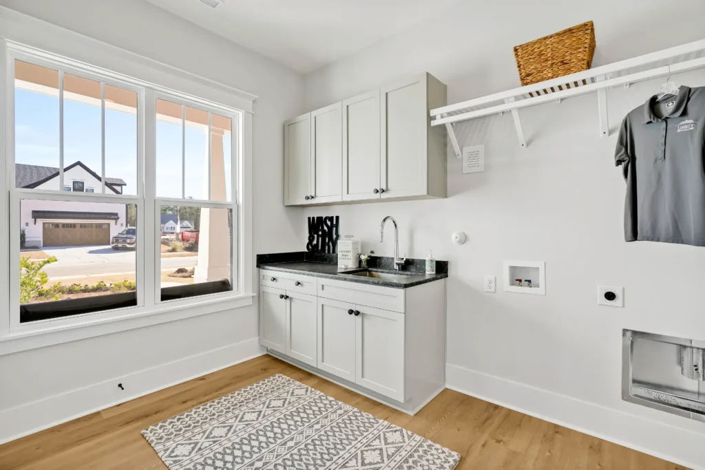 Let Us Reintroduce Ourselves 19 Bright modern laundry room with white cabinets, wood floors, and natural light.