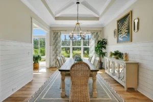 Bright coastal dining room with wooden table, rattan chairs, and airy natural light.